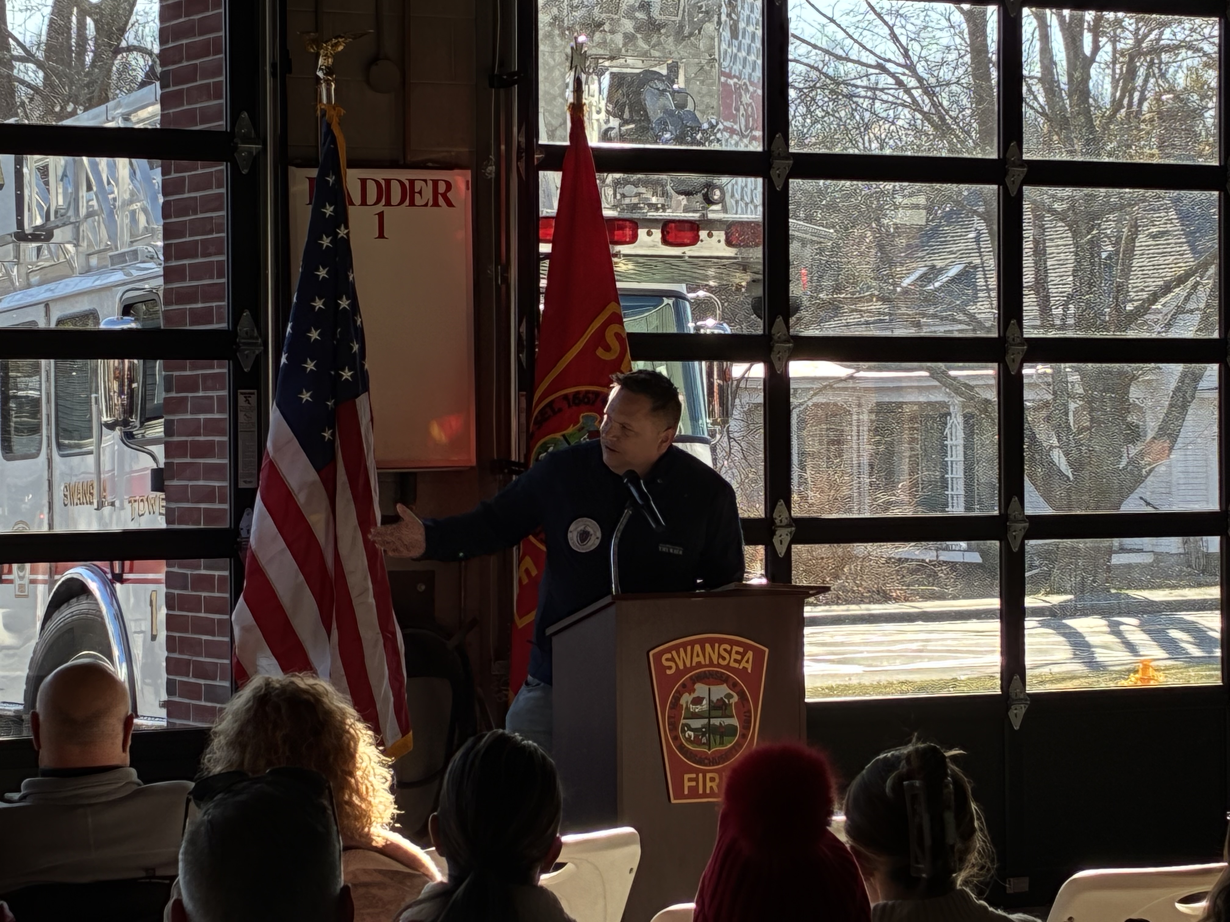 Justin Thurber speaking at a podium at the Swansea Fire Department station