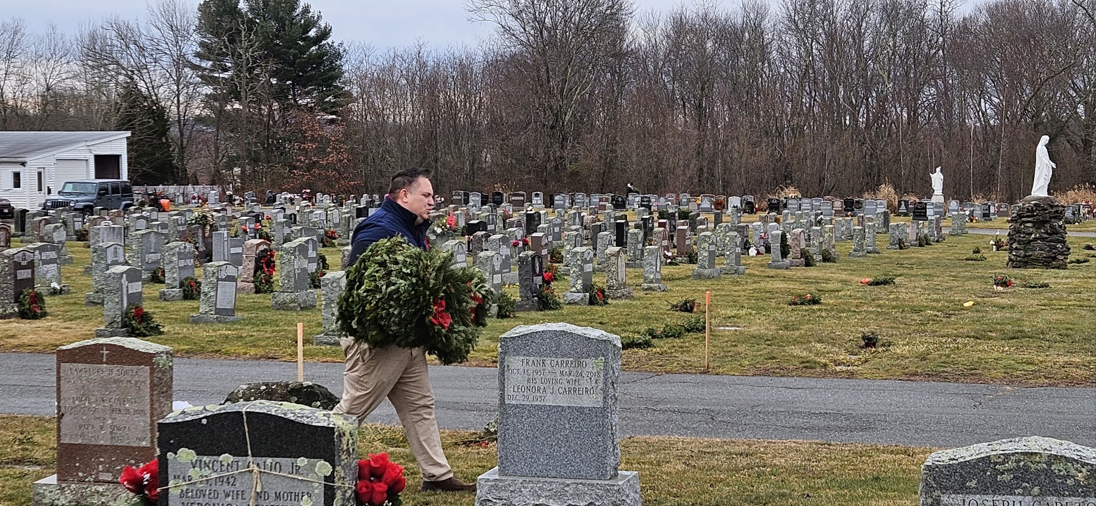 Justin Thurber walking through a cemetery carrying wreaths to place on veterans' graves